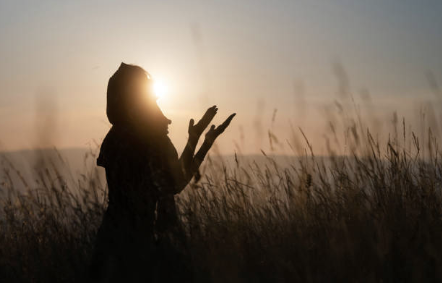 Woman praying at sunset